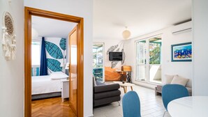 Ein modernes Zimmer mit einem Bett, einer Couch, einem Esstisch und einem Fernseher.