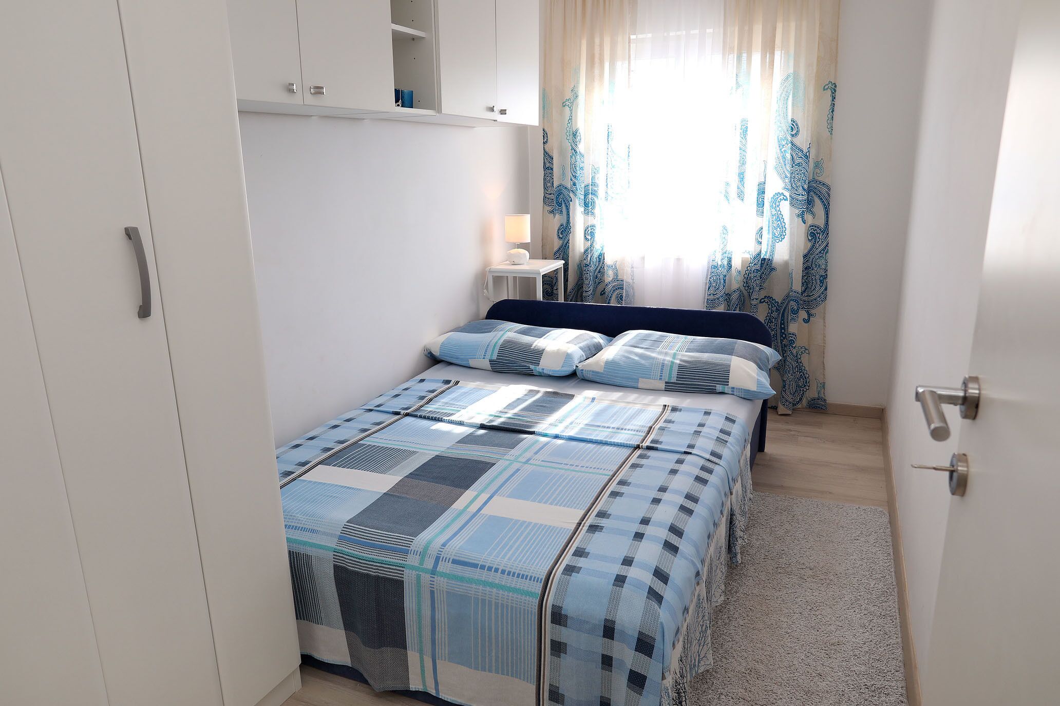 Une chambre à coucher avec un lit, une table de chevet avec une lampe et une armoire.
