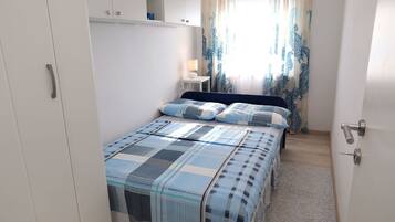 Une chambre à coucher avec un lit, une table de chevet avec une lampe et une armoire.