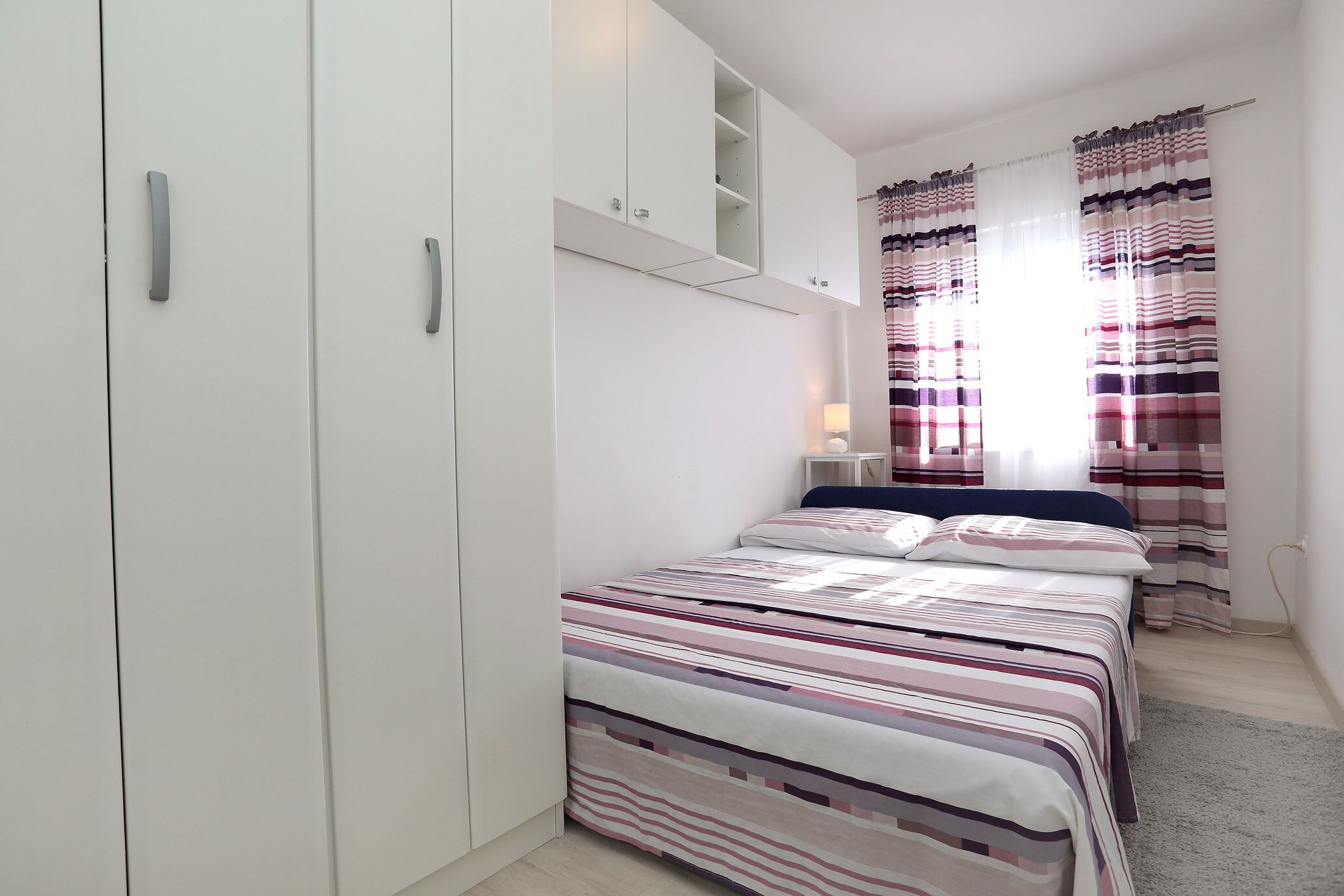 Un dormitorio con una cama, un armario y una mesita de noche.