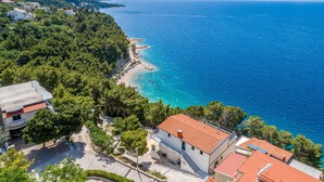 A coastal town with a beach, buildings, and a mountainous backdrop. - Rooms Sani - Double Room with Terrace and Sea View (S3) (Brela)