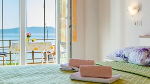 A hotel room with a bed, a table with chairs, and a view of the sea through a glass door. - Rooms Sani - Double Room with Terrace and Sea View (S3) (Brela)
