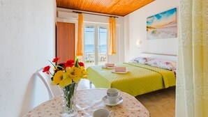A room with a bed, a table with a vase of flowers, and a painting on the wall. - Rooms Sani - Double Room with Terrace and Sea View (S3) (Brela)