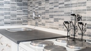 Een keuken met een modern design, voorzien van een roestvrijstalen fornuis, een spoelbak en een betegelde achterwand.