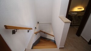 A staircase with wooden steps and handrails, leading to a bedroom with a bed and a lamp. - Apartment Mambo , Mljet - Duplex Apartment with Terrace and Sea View (Sobra)