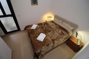 Une chambre à coucher avec un lit, une table de chevet, une lampe et une porte.