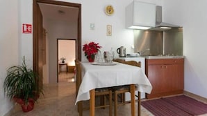 A small kitchen with a dining table, a potted plant, and a red flower centerpiece.