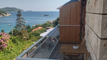 Un balcon avec vue sur la mer, une table en bois et un mur en pierre.