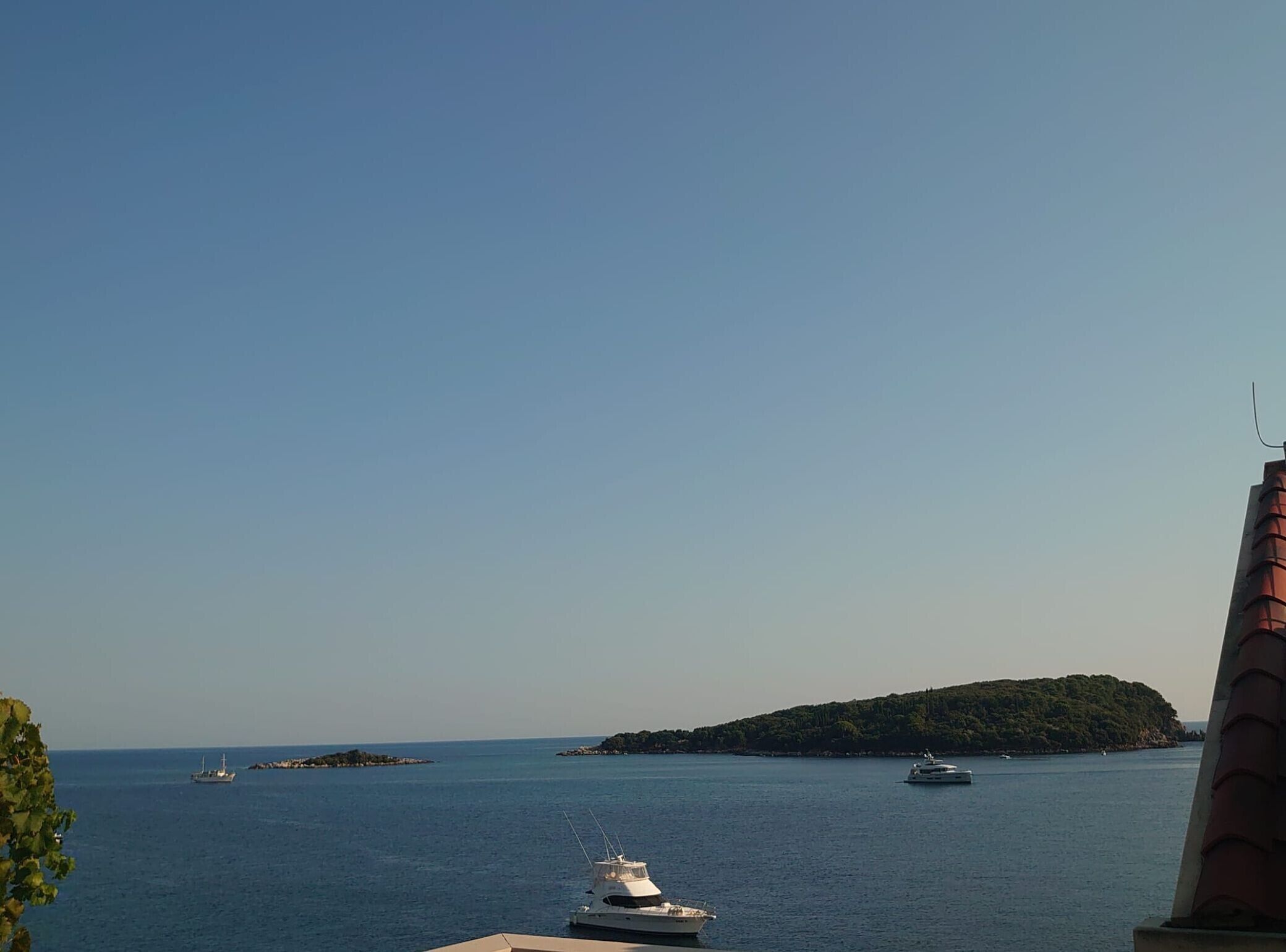 Vista costera con un yate amarrado cerca de una pequeña isla.