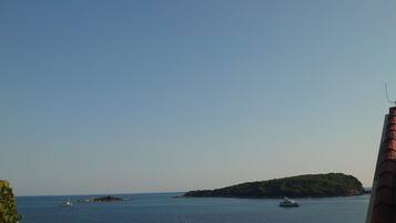 Vista costera con un yate amarrado cerca de una pequeña isla.
