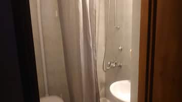 Une petite salle de bain avec des toilettes, un lavabo et une douche.