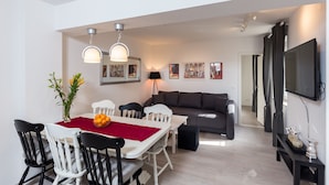 A modern living room with a dining area, a sofa, and a TV mounted on the wall. - Apartment Rea Zaton - Two-Bedroom Apartment (Zaton)