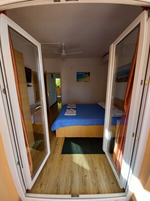 A bedroom with a bed, a ceiling fan, and a painting on the wall.