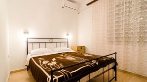 Un dormitorio con cama, mesita de noche y aire acondicionado.