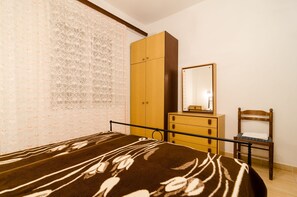 Un dormitorio con cama, armario, silla y espejo.