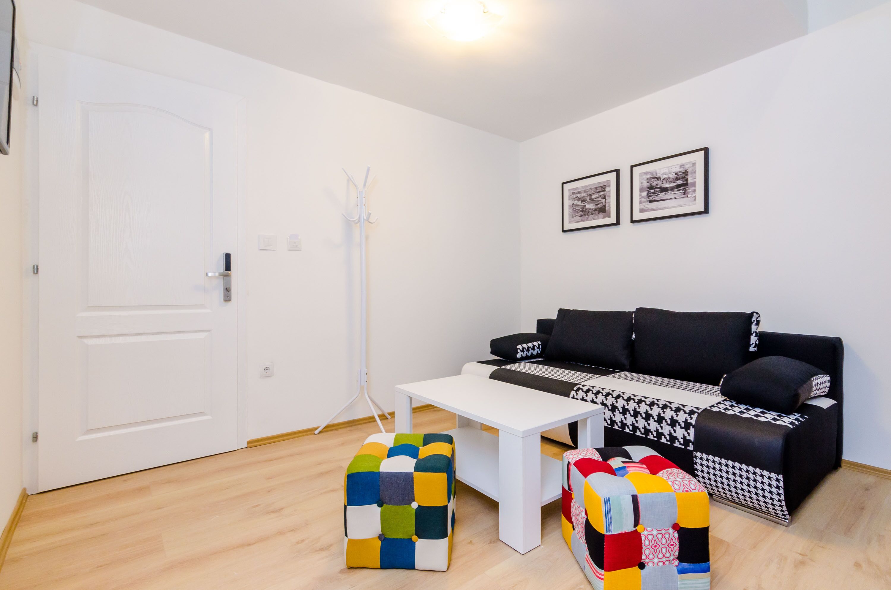 Una sala de estar moderna con un sofá negro, una mesa de centro blanca y otomanas coloridas.