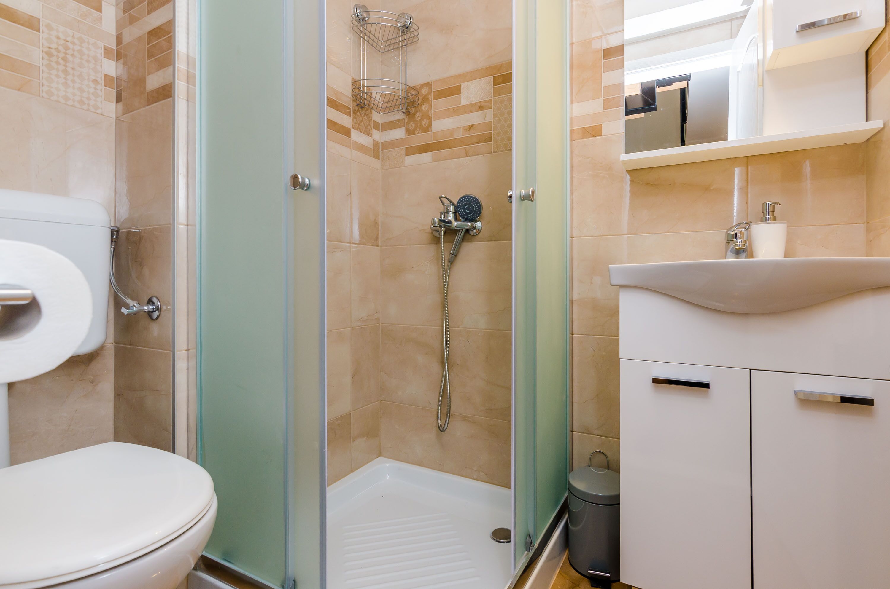 Un baño con inodoro, ducha con puerta de cristal y lavabo con espejo encima.