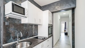 Una cucina moderna con forno a microonde integrato, lavello in acciaio inossidabile e mobili bianchi.