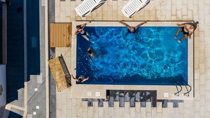 Una piscina all'aperto con quattro lettini prendisole e un solarium in legno.