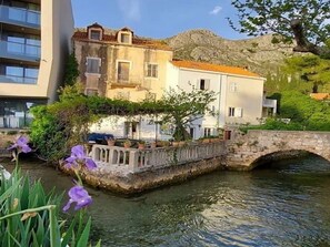 A stone bridge over a calm water body, with buildings on either side, one with a balcony and the other with a flat roof. - Apartments Subrenum - Superior Studio Apartment with Small Terrace (S4) (Mlini)