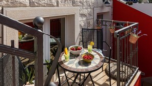 A stone building with a balcony, a round table with chairs, and a small garden area. - Apartments Subrenum - Superior Studio Apartment with Small Terrace (S4) (Mlini)