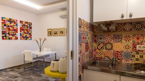 A modern kitchen with colorful tiles, a dining area with a white table and chairs, and a yellow side table with kitchen appliances. - Apartments Subrenum - Superior Studio Apartment with Small Terrace (S4) (Mlini)