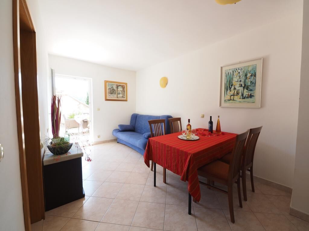 A dining area with a table set for two, a blue sofa, and a small plant on a side table.