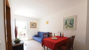 Zona pranzo con tavolo apparecchiato per due, un divano blu e una piccola pianta su un tavolino.