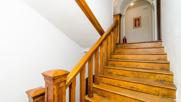 A wooden staircase with a handrail, leading to an arched doorway.
