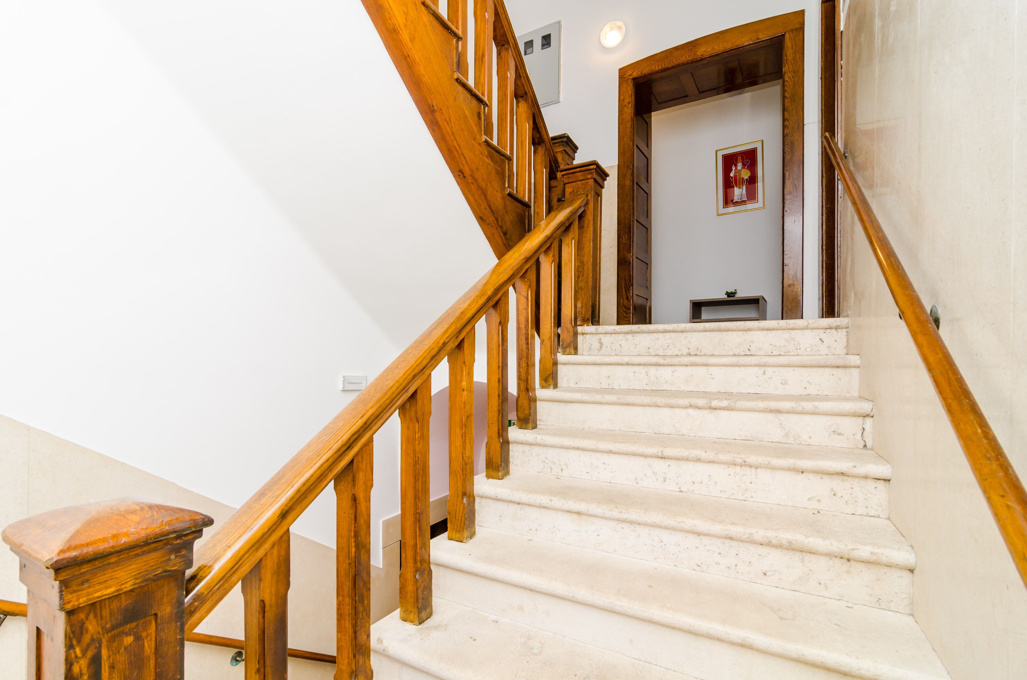 A staircase with wooden railings and white steps leading to a room with a door and a small table.