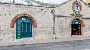 A building with a green door labeled "SOBE / ROOMS" and a sign for "CAFÉ BAR S.BATA" above the entrance.
