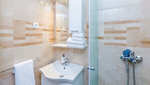 A bathroom with a sink, a glass shower enclosure, and a towel rack.