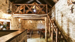 A rustic stone interior with a wooden staircase, stone walls, and a wooden table with chairs. - Superior Double Room with Balcony and Sea View (Soba 3) (Orasac)