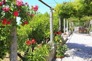 A garden with a pergola, stone pathway, and a table with chairs. - Superior Double Room with Balcony and Sea View (Soba 3) (Orasac)
