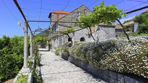 A stone building with a tiled roof, a cobblestone pathway, and a vine-covered wall. - Superior Double Room with Balcony and Sea View (Soba 3) (Orasac)