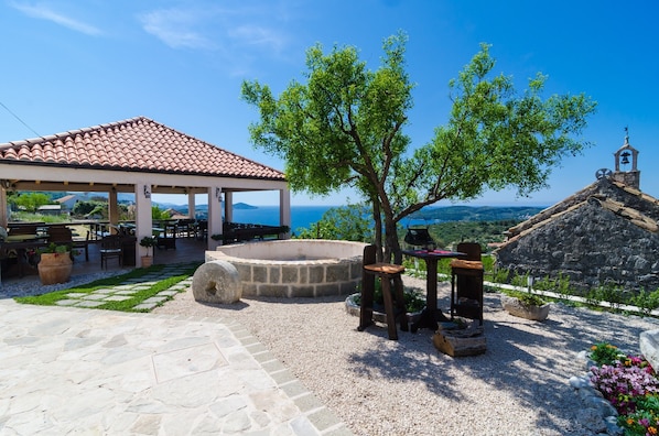 An outdoor patio with stone flooring, a covered seating area, a fire pit, and a view of the sea.
