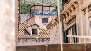 Une rue étroite bordée d’immeubles à l’architecture traditionnelle, notamment des toits recouverts de tuiles en terre cuite et des murs en pierre.