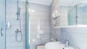 Une salle de bain moderne avec une douche à parois de verre, des toilettes blanches et un lavabo avec un miroir au-dessus.