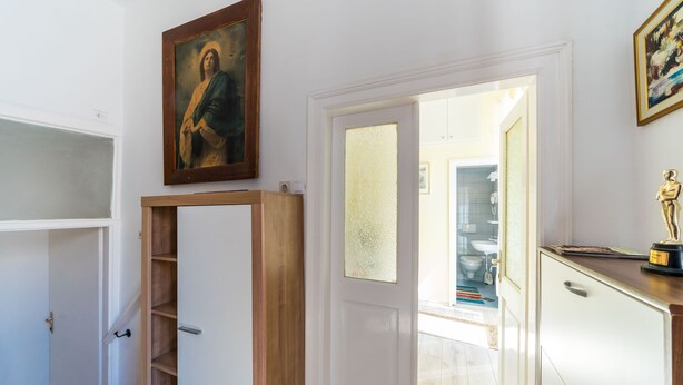 Un couloir avec une armoire en bois, une porte blanche et une petite statue posée sur un meuble.