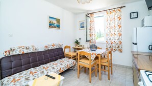 A compact living space with a sofa, dining table, chairs, and a kitchenette.