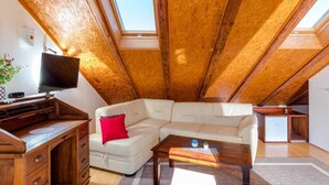 A cozy attic room with a wooden ceiling, a white sofa, a desk, and a television. - Rooms Miron - Deluxe Double Room with Balcony and Sea View (Sumartin)