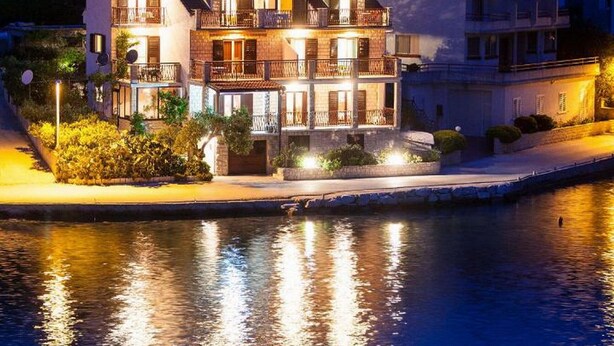Una propiedad frente al agua con varios pisos, balcones y una piscina.