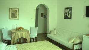 Ein Hotelzimmer mit einem Bett, einem weißen Sofa, einem Esstisch mit Stühlen und Bildern an den Wänden.