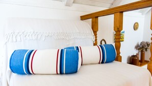 Una cama con ropa de cama blanca y dos almohadas a rayas.