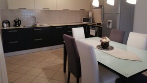 A modern kitchen with a dining area. It includes a sink, stove, microwave, refrigerator, and a dining table with chairs.