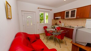 Eine kleine Küche mit Essbereich, einem roten Sofa und einem Kühlschrank.