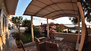 An outdoor patio with wicker furniture, a glass table, and a pergola.