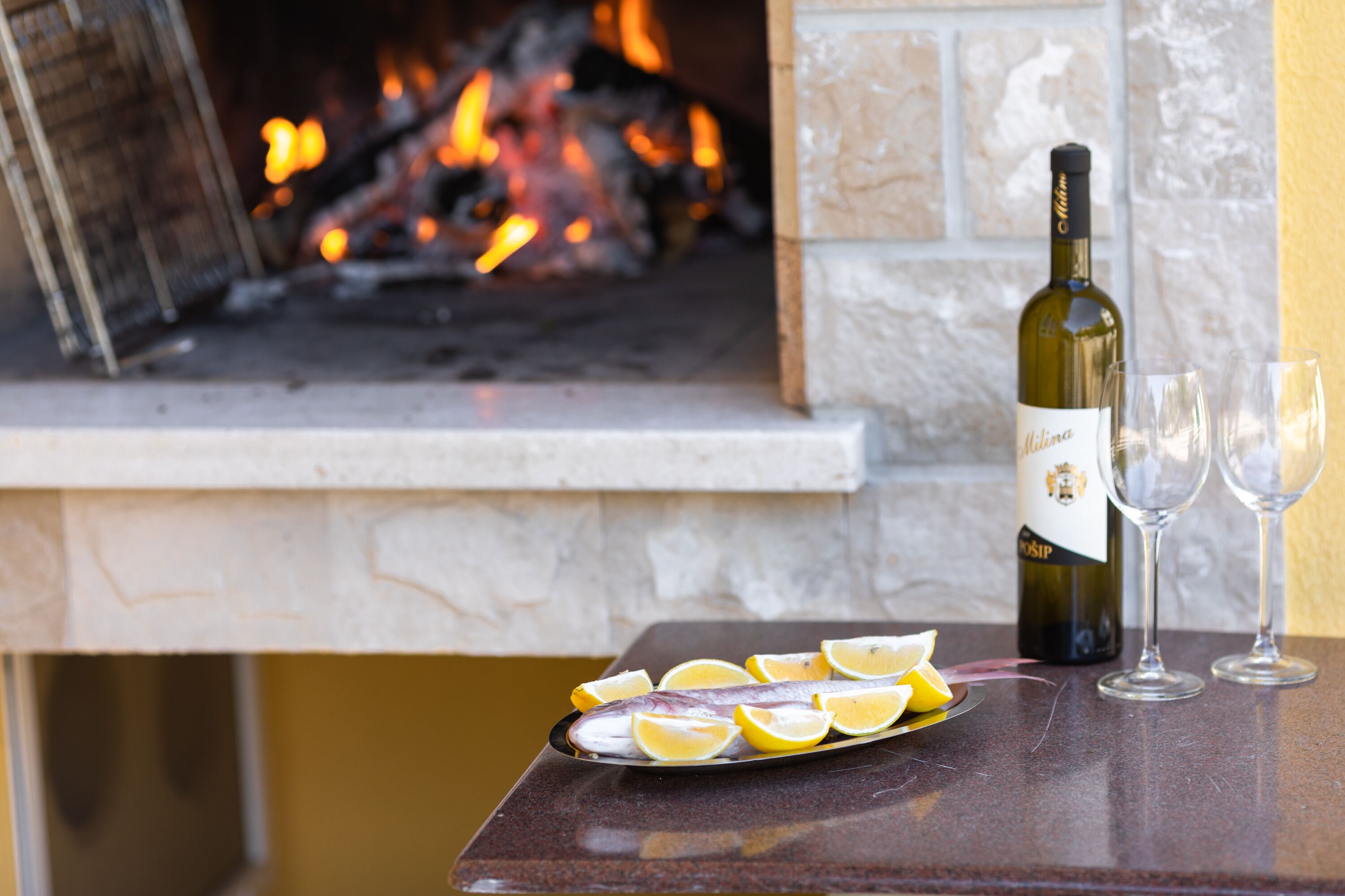 A table with a bottle of wine, two glasses, and a plate of lemon slices.