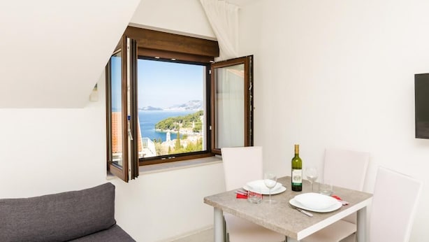 A dining area with a table, chairs, and a view of the sea. - Apartments & Rooms Cina - Studio Apartment with Sea View (Cavtat)