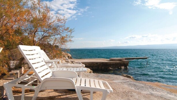 White lounge chairs on a rocky beach with a view of the sea and distant mountains. - Apartments Roko (ST) - Economy One Bedroom Apartment with Shared Terrace (A2) (Split)